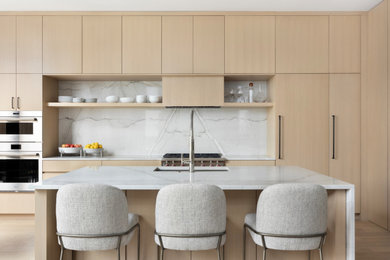 Open concept kitchen - mid-sized contemporary galley light wood floor and beige floor open concept kitchen idea in Denver with an undermount sink, flat-panel cabinets, light wood cabinets, quartzite countertops, beige backsplash, stone slab backsplash, paneled appliances, an island and beige countertops