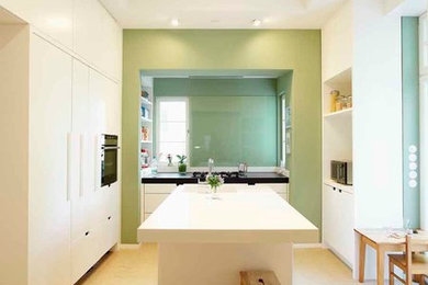 This is an example of an expansive contemporary separate kitchen in Frankfurt with flat-panel cabinets, white cabinets, green splashback, with island, a single-bowl sink and black appliances.