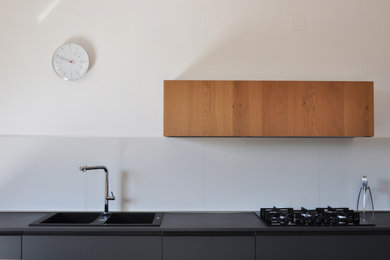 Immagine di una piccola cucina scandinava con lavello a doppia vasca, ante lisce, ante nere, top in quarzite, elettrodomestici neri, nessuna isola e top nero