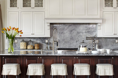 Example of a classic dark wood floor and brown floor kitchen design in Denver with raised-panel cabinets, white cabinets, gray backsplash, stainless steel appliances, an island and gray countertops
