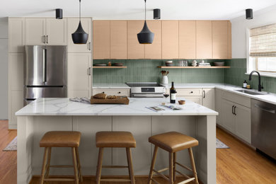 Eat-in kitchen - small mid-century modern l-shaped medium tone wood floor and brown floor eat-in kitchen idea in DC Metro with an undermount sink, flat-panel cabinets, light wood cabinets, quartz countertops, green backsplash, ceramic backsplash, stainless steel appliances, an island and white countertops