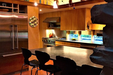 コロンバスにあるミッドセンチュリースタイルのおしゃれなキッチン (フラットパネル扉のキャビネット、中間色木目調キャビネット、ソープストーンカウンター、シルバーの調理設備、テラコッタタイルの床、オレンジの床) の写真