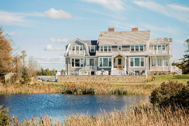 This is an example of a beach style two-storey grey house exterior in Boston with wood siding, a gambrel roof and a shingle roof.