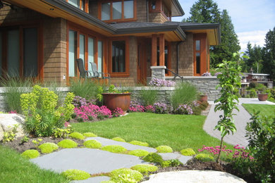 Design ideas for a large contemporary front yard full sun driveway in Vancouver with a retaining wall and natural stone pavers.