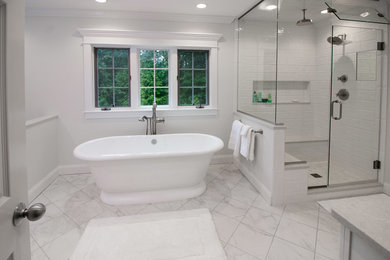 This is an example of a mid-sized contemporary master bathroom in Boston with raised-panel cabinets, white cabinets, a freestanding tub, an alcove shower, a two-piece toilet, white tile, porcelain tile, white walls, porcelain floors, an undermount sink, engineered quartz benchtops, white floor, a hinged shower door and white benchtops.
