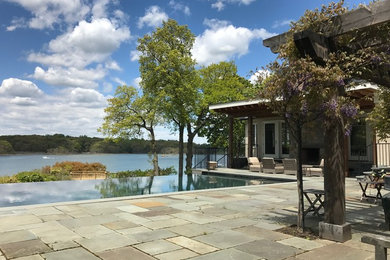 Photo of a large contemporary side yard rectangular infinity pool in New York with natural stone pavers.