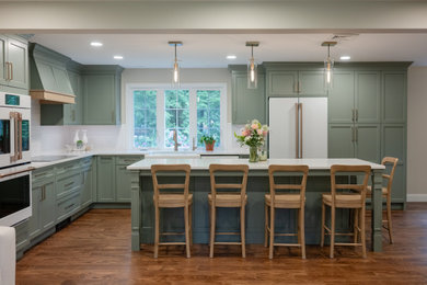 Kitchen - transitional l-shaped medium tone wood floor and brown floor kitchen idea in Other with a farmhouse sink, recessed-panel cabinets, green cabinets, white backsplash, white appliances, an island and white countertops