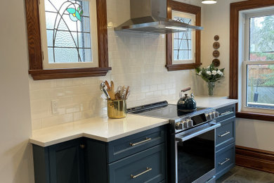 Example of a classic porcelain tile kitchen design in Toronto with an undermount sink, shaker cabinets, blue cabinets, quartz countertops, white backsplash, subway tile backsplash, stainless steel appliances and white countertops