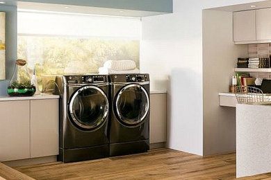 Laundry room - modern light wood floor laundry room idea in Tampa with flat-panel cabinets and a side-by-side washer/dryer