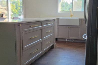 Example of a mid-sized minimalist l-shaped medium tone wood floor and brown floor eat-in kitchen design in Montreal with a farmhouse sink, gray cabinets, quartzite countertops, an island and white countertops