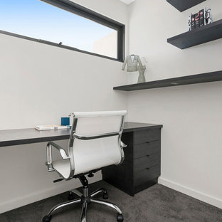 This is an example of a mid-sized contemporary home office in Melbourne with white walls, carpet, a built-in desk and grey floor.