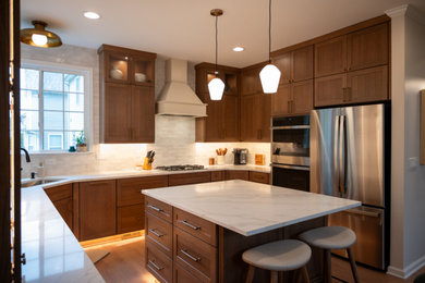 Eat-in kitchen - mid-sized traditional u-shaped vinyl floor and brown floor eat-in kitchen idea in Detroit with an undermount sink, brown cabinets, quartzite countertops, white backsplash, ceramic backsplash, stainless steel appliances, an island and white countertops