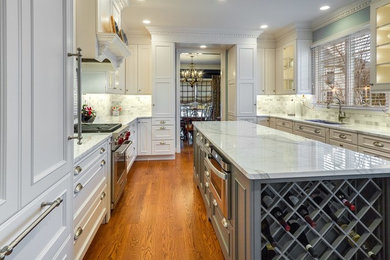 Example of a large u-shaped medium tone wood floor kitchen design in Philadelphia with a double-bowl sink, glass-front cabinets, white cabinets, marble countertops, white backsplash, stainless steel appliances and an island