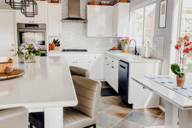 Inspiration for a large contemporary u-shaped porcelain tile and multicolored floor eat-in kitchen remodel in Las Vegas with an undermount sink, raised-panel cabinets, white cabinets, quartzite countertops, gray backsplash, marble backsplash, stainless steel appliances, an island and white countertops