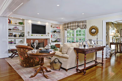 Inspiration for a large transitional enclosed medium tone wood floor family room remodel in New York with beige walls, a standard fireplace, a brick fireplace and a media wall
