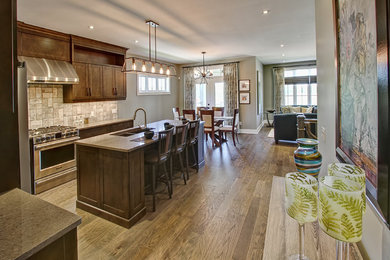 Mid-sized arts and crafts l-shaped dark wood floor and brown floor open concept kitchen photo in Toronto with a double-bowl sink, shaker cabinets, dark wood cabinets, beige backsplash, ceramic backsplash, stainless steel appliances and an island