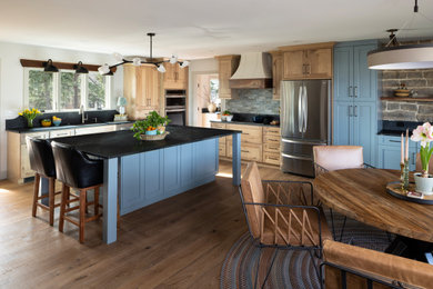 Eat-in kitchen - transitional l-shaped medium tone wood floor and brown floor eat-in kitchen idea in Omaha with stainless steel appliances, an island, black countertops, shaker cabinets and soapstone countertops