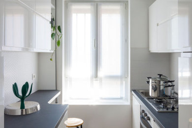 Esempio di una piccola cucina parallela design chiusa con lavello a vasca singola, ante a filo, ante bianche, top in quarzo composito, paraspruzzi bianco, paraspruzzi con piastrelle a mosaico, elettrodomestici in acciaio inossidabile, pavimento in gres porcellanato, nessuna isola, pavimento marrone e top grigio