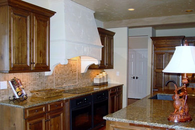 Huge elegant medium tone wood floor kitchen photo in Wichita with an undermount sink, raised-panel cabinets, medium tone wood cabinets, granite countertops, beige backsplash, stone tile backsplash, paneled appliances and an island