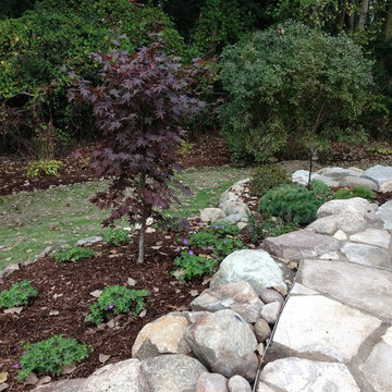 Extended patio with boulder wall and new plantings