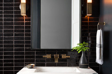 Example of a minimalist black tile powder room design in Austin with an integrated sink and white countertops