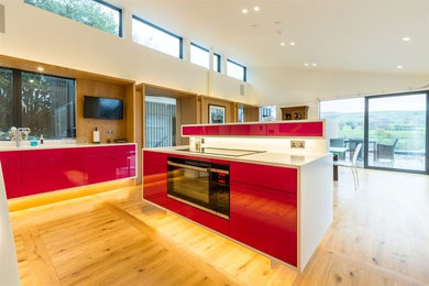 Inredning av ett modernt stort kök med öppen planlösning, med en köksö, en nedsänkt diskho, rosa stänkskydd, färgglada vitvaror och ljust trägolv