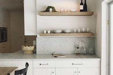 Inspiration for a large cottage galley ceramic tile and beige floor open concept kitchen remodel in Miami with an undermount sink, shaker cabinets, white cabinets, marble countertops, white backsplash, wood backsplash, stainless steel appliances and a peninsula