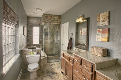 Design ideas for a large country master bathroom in Wichita with recessed-panel cabinets, medium wood cabinets, a drop-in tub, a corner shower, a two-piece toilet, grey walls, ceramic floors, an integrated sink, granite benchtops and a hinged shower door.