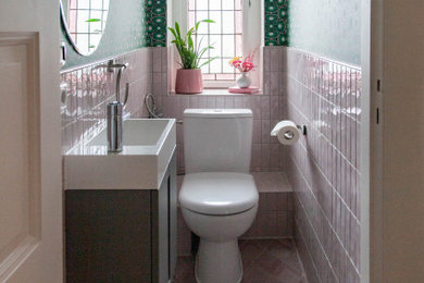 Eklektisk inredning av ett litet vit vitt en-suite badrum, med släta luckor, grå skåp, en toalettstol med hel cisternkåpa, rosa kakel, keramikplattor, gröna väggar, klinkergolv i keramik, ett integrerad handfat, laminatbänkskiva och rosa golv