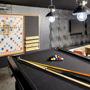 Home theater - large industrial enclosed concrete floor home theater idea in Sydney with black walls and a wall-mounted tv