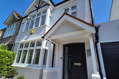 Expansive and gey classic render house exterior in London with three floors, a pitched roof, a tiled roof and a black roof.