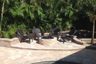 Example of a mid-sized classic backyard concrete paver patio design in Tampa with a fire pit and no cover