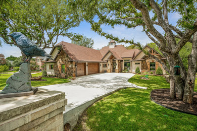 Example of a mid-sized eclectic multicolored one-story stone and shingle house exterior design in Dallas with a clipped gable roof, a mixed material roof and a brown roof