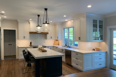 Moderne Küche mit Schrankfronten mit vertiefter Füllung, weißen Schränken, Küchenrückwand in Weiß, Küchengeräten aus Edelstahl, dunklem Holzboden, Kücheninsel und weißer Arbeitsplatte in New York
