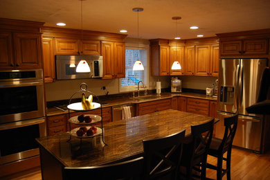 Example of a mid-sized classic l-shaped light wood floor and brown floor open concept kitchen design in Boston with an undermount sink, raised-panel cabinets, medium tone wood cabinets, granite countertops, stone slab backsplash, stainless steel appliances, an island and brown backsplash