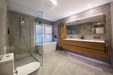 Design ideas for a large modern bathroom in Melbourne with light wood cabinets, a freestanding tub, an open shower, a wall-mount toilet, gray tile, porcelain tile, grey walls, porcelain floors, a drop-in sink, engineered quartz benchtops, grey floor, a hinged shower door and white benchtops.