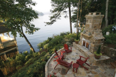 Example of a large arts and crafts backyard stone patio design in Calgary with a fire pit and no cover