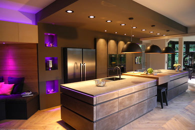 Zweizeilige, Geräumige Moderne Wohnküche mit Einbauwaschbecken, flächenbündigen Schrankfronten, schwarzen Schränken, Mineralwerkstoff-Arbeitsplatte, schwarzen Elektrogeräten, braunem Holzboden, Kücheninsel, braunem Boden und schwarzer Arbeitsplatte in Sonstige