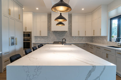 Example of a large trendy u-shaped yellow floor eat-in kitchen design in Toronto with a drop-in sink, shaker cabinets, quartz countertops, gray backsplash, ceramic backsplash, stainless steel appliances, an island and white countertops