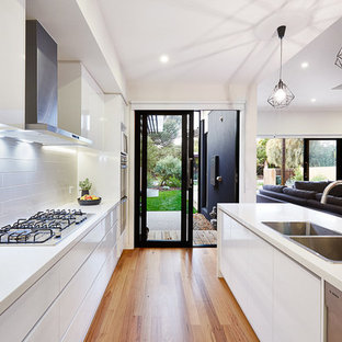 Mid-sized modern kitchen pantry ideas - Example of a mid-sized minimalist single-wall light wood floor kitchen pantry design in Melbourne with a double-bowl sink, raised-panel cabinets, white cabinets, marble countertops, white backsplash, ceramic backsplash, stainless steel appliances and an island