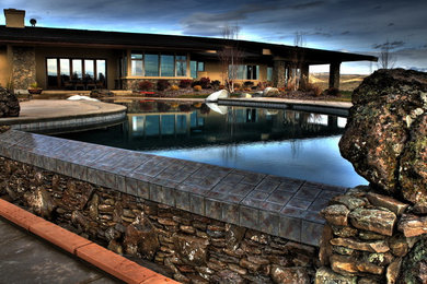 This is an example of a large modern backyard custom-shaped pool in Boise with concrete pavers.