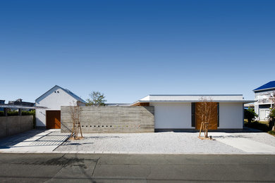 Trendy beige one-story flat roof photo in Other