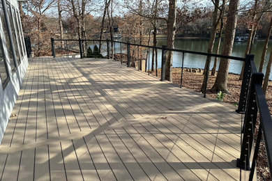 Example of a backyard ground level cable railing deck design in Charlotte with no cover