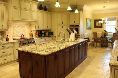 Example of a large classic travertine floor and beige floor eat-in kitchen design in Orange County with an undermount sink, raised-panel cabinets, beige cabinets, granite countertops, beige backsplash, stone tile backsplash, stainless steel appliances and an island