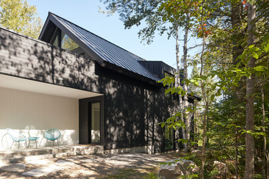 Large contemporary black two-story wood and clapboard exterior home idea in Montreal with a metal roof and a black roof