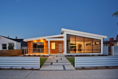 This is an example of a large midcentury one-storey white exterior in Orange County with wood siding.