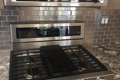 Eat-in kitchen - large contemporary eat-in kitchen idea in San Francisco with metallic backsplash, metal backsplash, stainless steel appliances and gray countertops