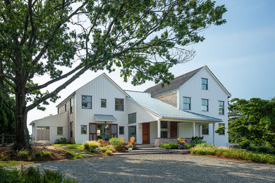 Inspiration for a mid-sized coastal white three-story wood exterior home remodel in Other with a mixed material roof