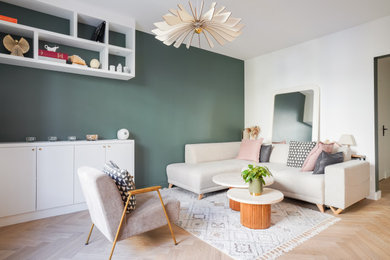 Inspiration pour un salon gris et rose minimaliste de taille moyenne et ouvert avec un mur vert, parquet clair, aucune cheminée, un téléviseur indépendant, un sol beige et éclairage.