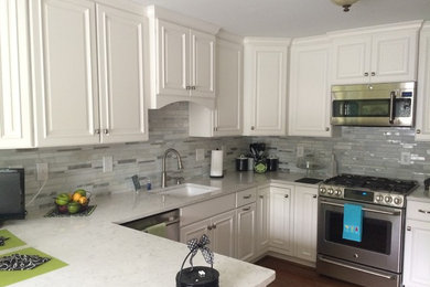 Inspiration for a mid-sized contemporary u-shaped medium tone wood floor enclosed kitchen remodel in Louisville with an undermount sink, recessed-panel cabinets, white cabinets, quartzite countertops, white backsplash, glass tile backsplash, stainless steel appliances and a peninsula